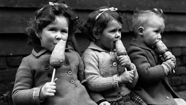 Children eating a wartime treat: carrots on sticks